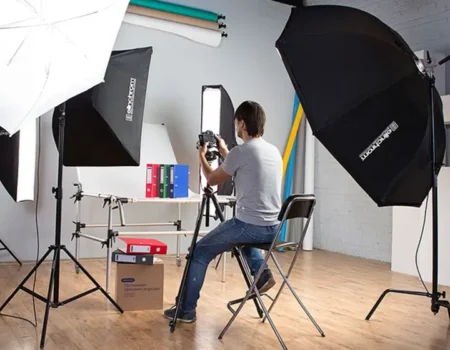 Полноценная фотостудия с рулонными фонами, несколькими зонтами и софтбоксами Elinchrom, фотограф снимает канцелярские папки — такой масштаб избыточен для карточек товара: 90% задач закрывает один моноблок и стол.